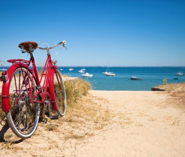 vélo rouge sur chemin en sable et mer au loin -  hotel la baule escoublac